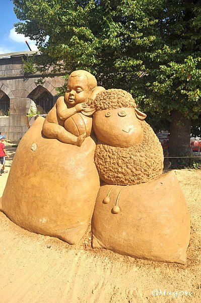 Sand Festival в России: скульптура мальчика и овцы из песка у арочного здания